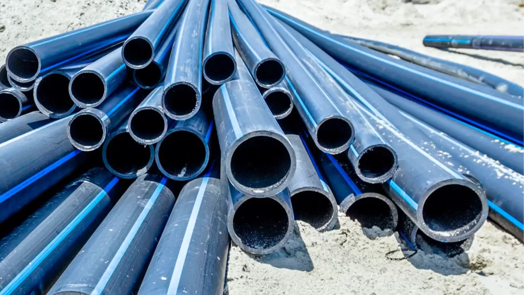 Tubi in polietilene blu accatastati su sabbia