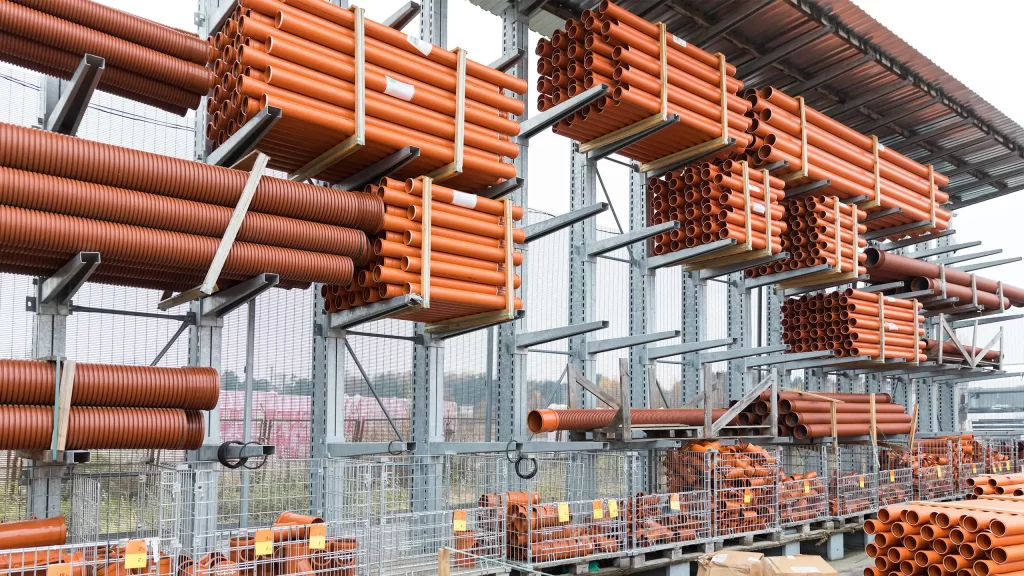 Magazzino con tubi in PVC arancioni organizzati su scaffali