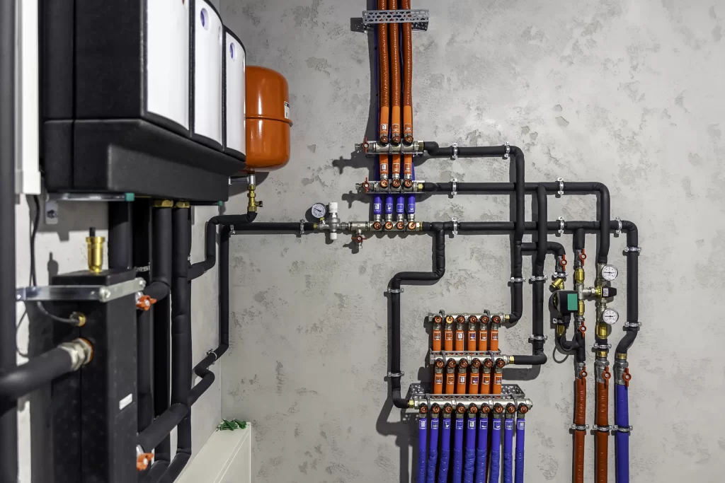 Impianto termoidraulico con tubazioni isolate, collettori e vaso di espansione rosso.